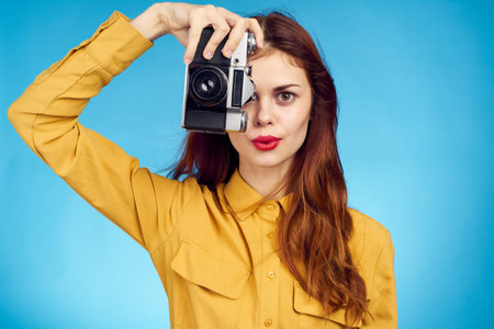 pretty woman photographer with camera in yellow shirt on blue background