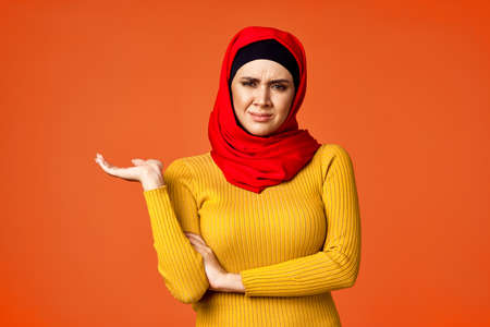 muslim woman in red hijab posing gesturing with hands isolated backgroundの写真素材