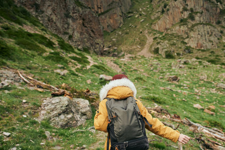 woman in a jacket with a backpack hiking travel in the mountains