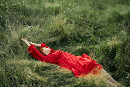 woman in a black dress lies in a field nature fashion summerの写真素材