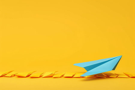 Blue paper airplane on yellow background with copy space for your text or design conceptの素材