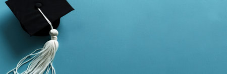 Graduation cap and tassel on a blue background with copy space for text education achievement conceptの素材