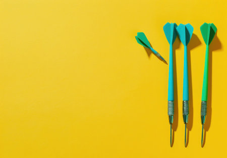Three blue darts arranged on a bright yellow background, with one dart slightly separated from the rest, creating a playful and dynamic compositionの素材