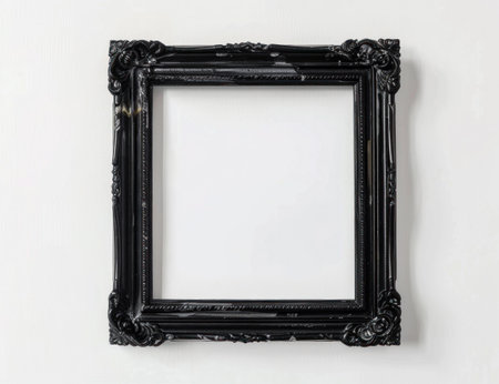 Empty ornate black picture frame on a white wall, showcasing elegance and simplicity in modern interior designの素材
