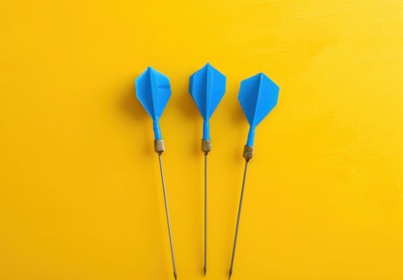 Three blue darts arranged on a vibrant yellow background, symbolizing precision and target achievementの素材