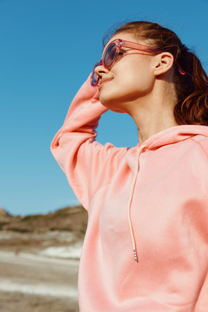 Woman in pink sweatshirt and sunglasses standing looking up at sky on a sunny dayの写真素材