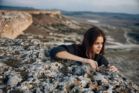 Woman sitting on rock in stunning mountain landscape, contemplating natures beautyの写真素材