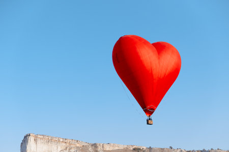 romantic heart balloon soars above majestic mountain rangeの写真素材
