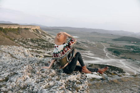 Serene woman admiring breathtaking panoramic view from mountaintop over lush valley and distant peaksの写真素材