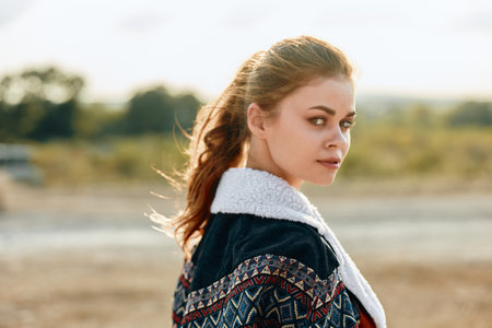 Lonely woman in sweater standing in field with car in background on a cloudy day