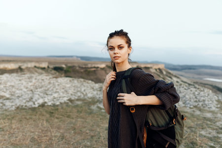 female hiker enjoying breathtaking mountain vista from hilltop perch with backpack