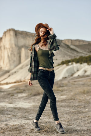Young woman in plaid shirt and jeans stands confidently in the desert