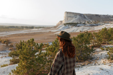 Outdoor adventure woman in plaid shirt and hat standing in front of majestic rock formationの写真素材
