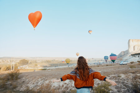 Woman standing in field with heart-shaped balloon in background on a sunny dayの写真素材