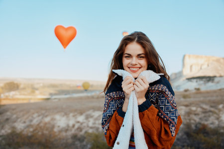 Joyful woman holding heartshaped balloon against stunning mountain backdropの写真素材