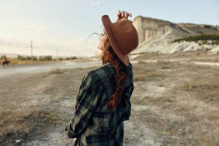 desert wanderer woman in plaid shirt and hat standing alone in arid landscapeの写真素材
