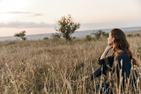 Solitude in nature woman sitting in field gazes at distant horizon, embodying peace and serenityの写真素材