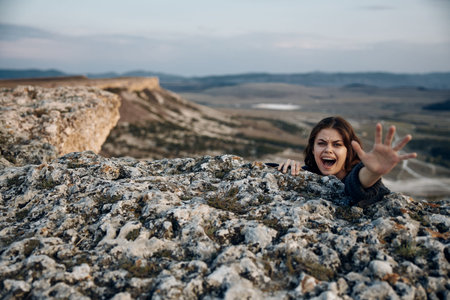 Mysterious woman emerges from rocky mountain crevice with arms extended in natures beautyの写真素材