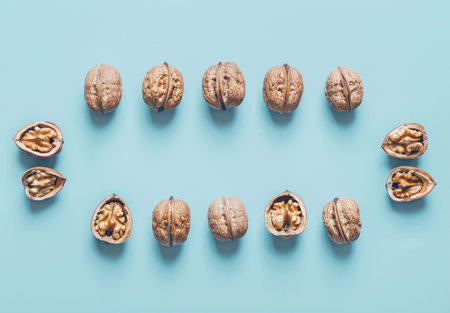 A creative arrangement of walnuts on a light blue background showcasing both whole and partially opened nutsの素材