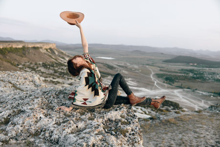 freedom at the summit woman celebrating success with arms raised and hat in handの写真素材