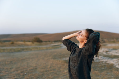 Woman standing in awe in the vast open field, hands on head, gazing at the expansive skyの写真素材