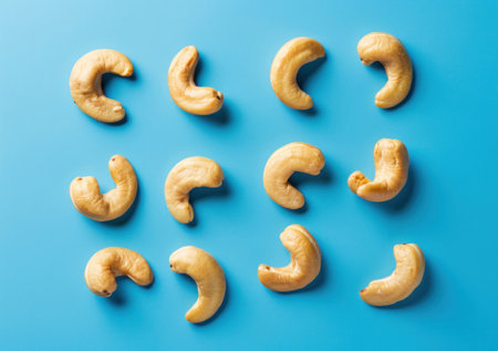 Cashew nuts arranged in a pattern on a vibrant blue backgroundの素材