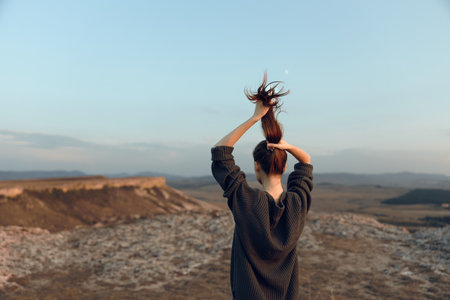empowered woman standing triumphantly on hilltop with arms raisedの写真素材