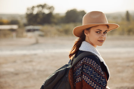 Wanderlust woman in hat and backpack with sunlight in background