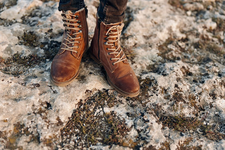 Winter wonderland joyful person in brown boots standing with arms raised on snowy ground
