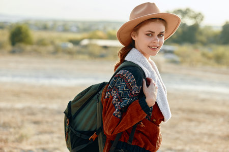 Happy hiker in a sunlit field with backpack and hat, enjoying the great outdoorsの写真素材