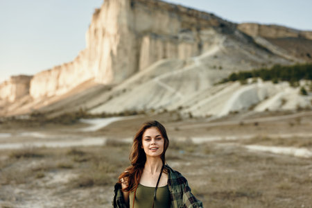 Confident woman enjoying the view of a majestic mountain with hands on hips and a cheerful smile