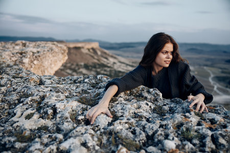 woman sitting on rocky ledge with arms outstretchedの写真素材