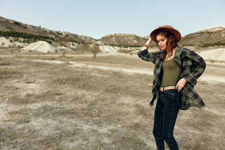 Serene woman in plaid shirt and hat standing gracefully in vast open field