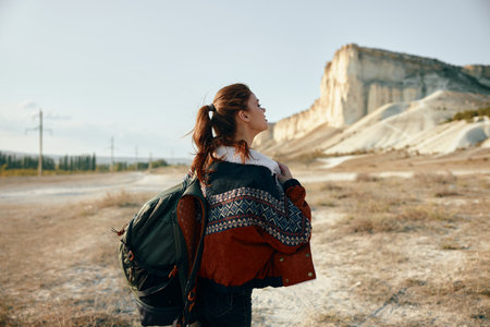Adventure awaits woman with backpack admiring stunning desert view from mountain summitの写真素材