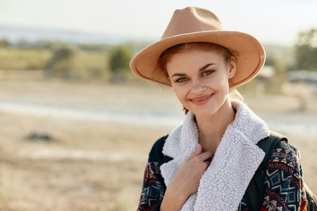 stylish young woman in hat and scarf enjoying the scenic countrysideの写真素材