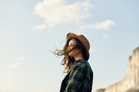 Woman in plaid shirt and hat standing on beach on sunny day