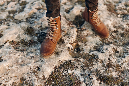 solitary figure in snowy landscape wearing brown boots and jeans atop hill