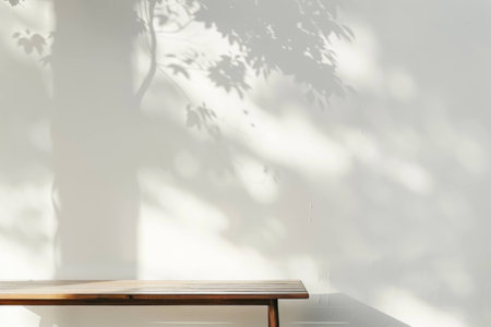 Minimalist wooden bench against a light wall with soft tree shadow, creating a calm and serene atmosphere for relaxation or reflection.の素材
