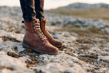 Explorer gazing into the horizon from a rocky hilltop, wearing sturdy boots and ready for adventureの写真素材