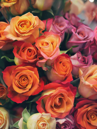Colorful bouquet of fresh roses in vibrant shades of orange and pink, symbolizing love and beauty in a romantic arrangement.の素材