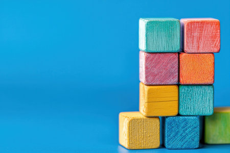 Colorful wooden blocks stacked on a vibrant blue background, showcasing creativity and playfulness, ideal for children s education and developmentの素材
