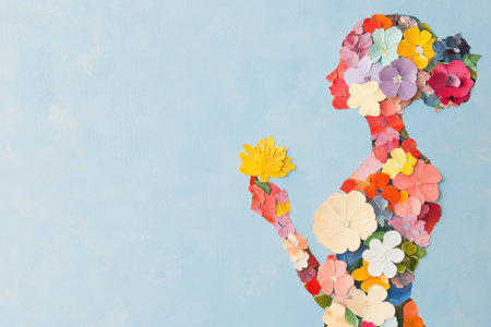 Elegant silhouette of a woman made from colorful paper flowers, symbolizing beauty, femininity, and nature against a soft blue backgroundの素材