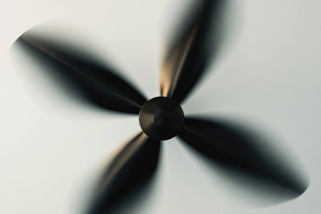 Black ceiling fan blades rotating swiftly against a neutral background, capturing movement and modern home decor elements for interior design enthusiastsの素材
