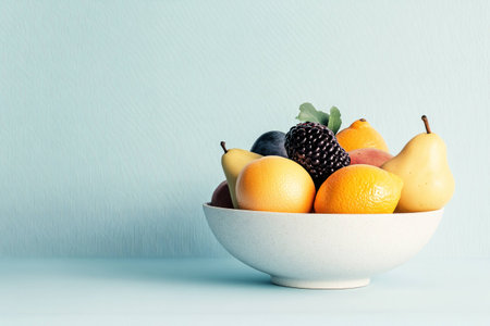 Fresh fruits in a white bowl on a light blue background, showcasing colorful pears, oranges, and berries for healthy eating conceptの素材