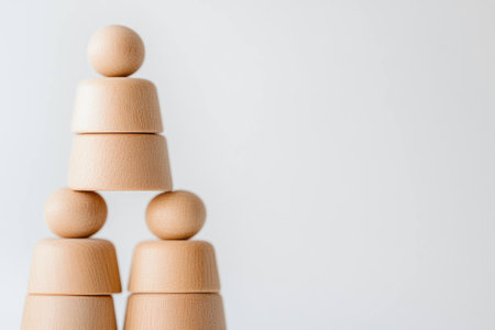 Minimalist wooden figures arranged in a pyramid shape on a light background, representing balance and stability, ideal for concepts of teamwork and collaborationの素材