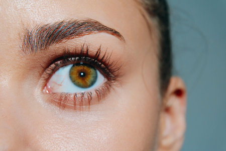 Close-up of a womans eye showcasing vibrant green iris, emphasizing natural beauty and eye health.