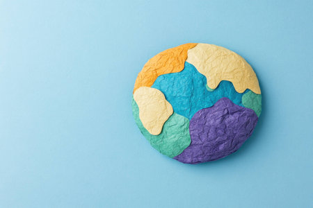 Colorful paper clay world globe on a blue background, representing creativity, art, and sustainability in design conceptsの素材
