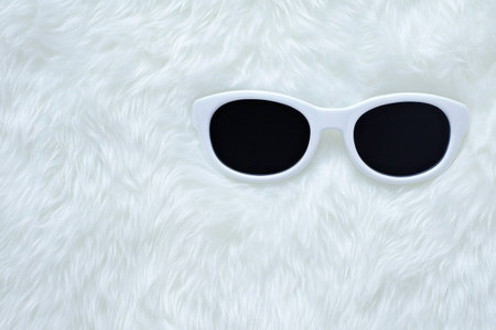 Stylish white sunglasses on a soft white fur background, perfect for summer fashion and personal style enhancement Bright and trendy accessoriesの素材