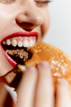 Happy woman enjoying a delicious burger with a bright smile, showcasing food delight in stunning close-up format.の写真素材