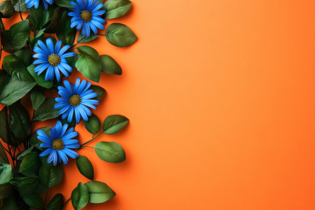 Vibrant blue flowers with green leaves against an orange background, creating a lively and fresh spring vibe, perfect for seasonal decor or nature themed projectsの素材